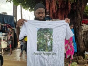 A man holding up a t-shirt with an image of a tree.